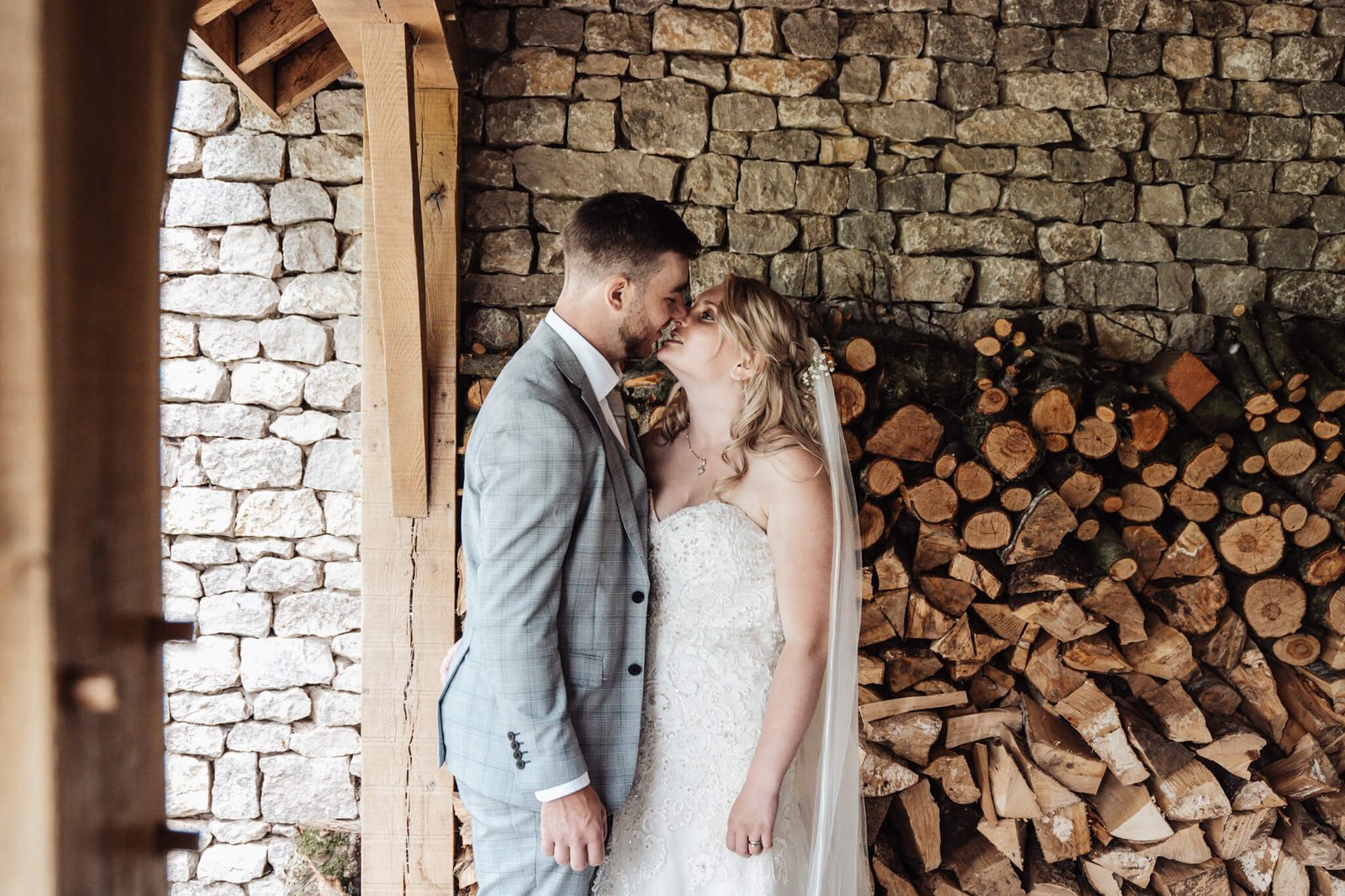 Bride & Groom Kissing By Logs at The Fleece Ruleholme
