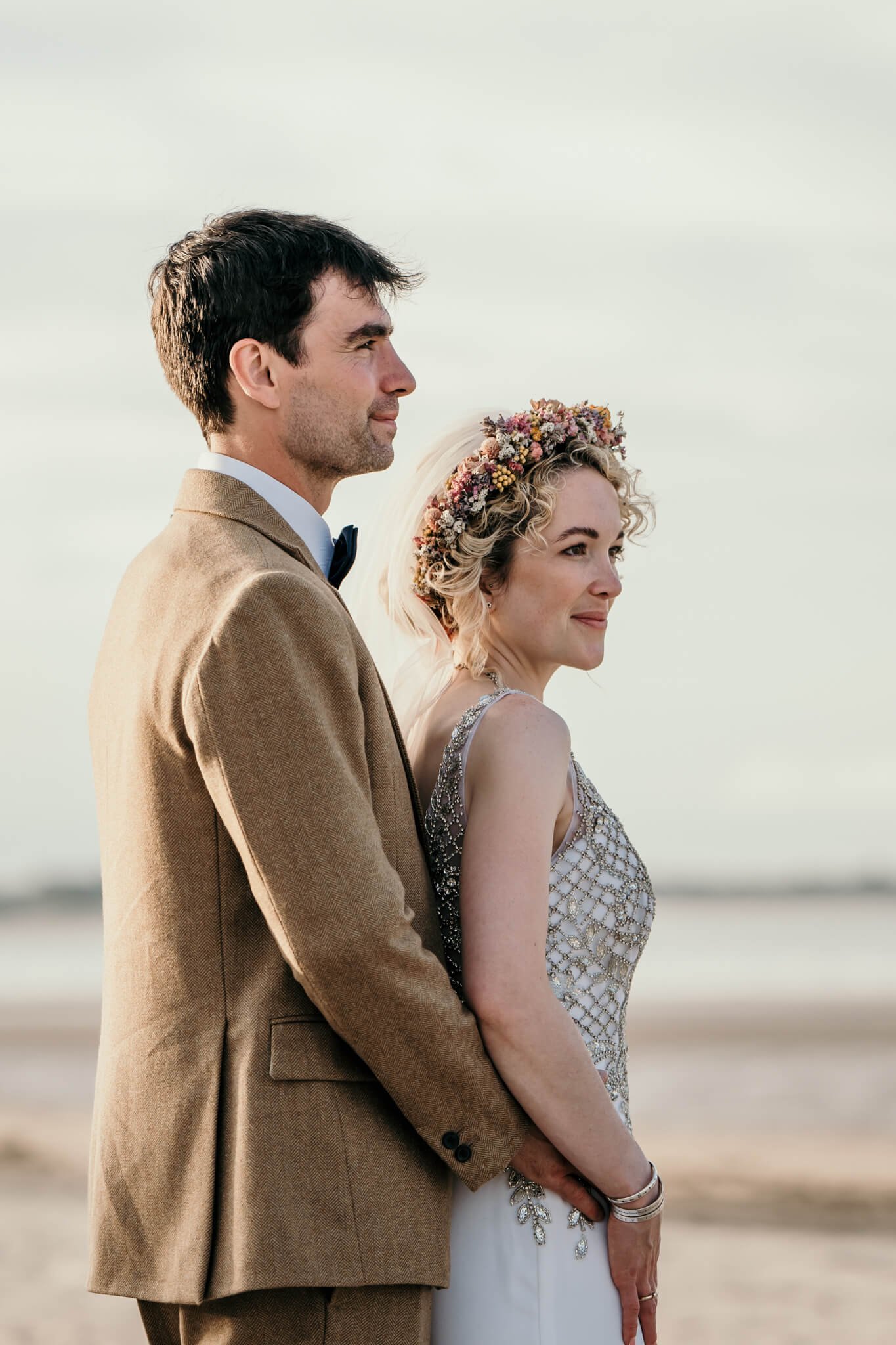 bride and groom embracing on beach at newton hall northumberland